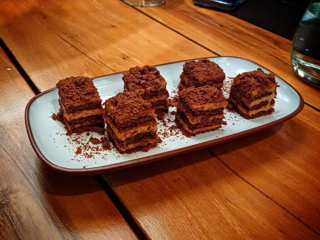 Tiny chocotorta portions cut into squares on a white tray.