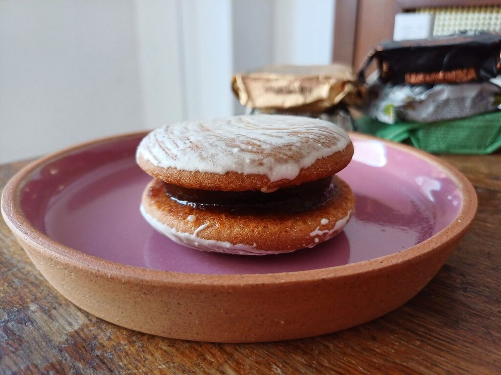 Alfajor cordobés with quince jam filling displayed on a pink plate.