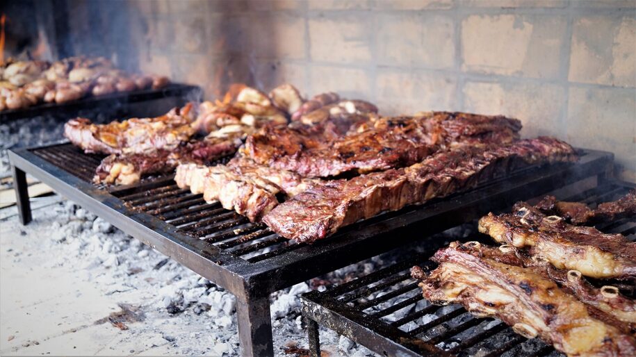 Lit Argentine parrilla with meat cuts and sausages on top.