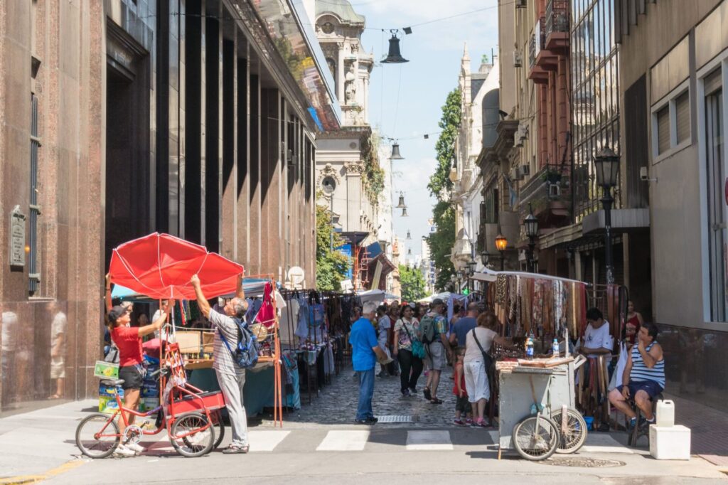 Customers browse goods while some artisans set up shop at the Defensa Street Fair.